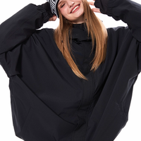 Person wearing a black oversized jacket and a beanie with text, standing against a white background