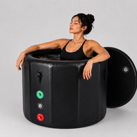 Woman sitting in a black inflatable ice tub on a gray background