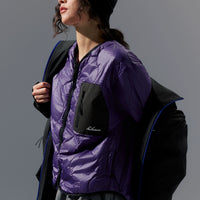 Person wearing a purple jacket with a black backpack against a gray background