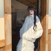 Person wearing a white skiing outfit and leopard print helmet standing in a wooden doorway.