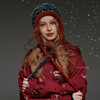 Person wearing a red hooded jacket with snowflake patterns against a dark background.