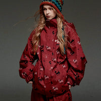 Person wearing a red snowsuit with a pattern, standing against a dark background.