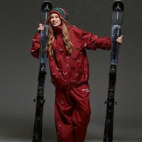 Person in a red ski outfit holding skis against a gray background