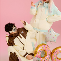 Two people in colorful outfits with large inflatable letters on a pink background