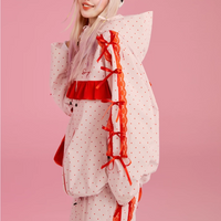 Person wearing a stylish outfit with polka dot jacket and red accents on a pink background, featuring Swag L Brand Autumn Winter Collections.