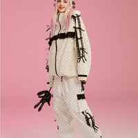 Person wearing a stylish winter outfit with polka dot pattern on a pink background
