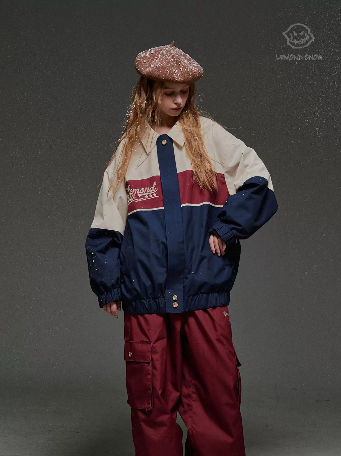 Person wearing a colorful jacket and red pants on a gray background