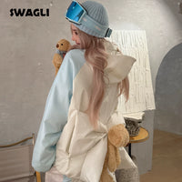 Person wearing a light-colored jacket with fluffy texture, holding a teddy bear, in a room with a neutral color scheme.