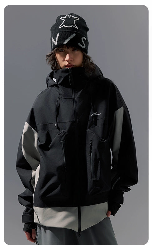 Person wearing a black jacket with brand logos on a gray background