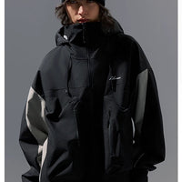 Person wearing a black jacket with brand logos on a gray background