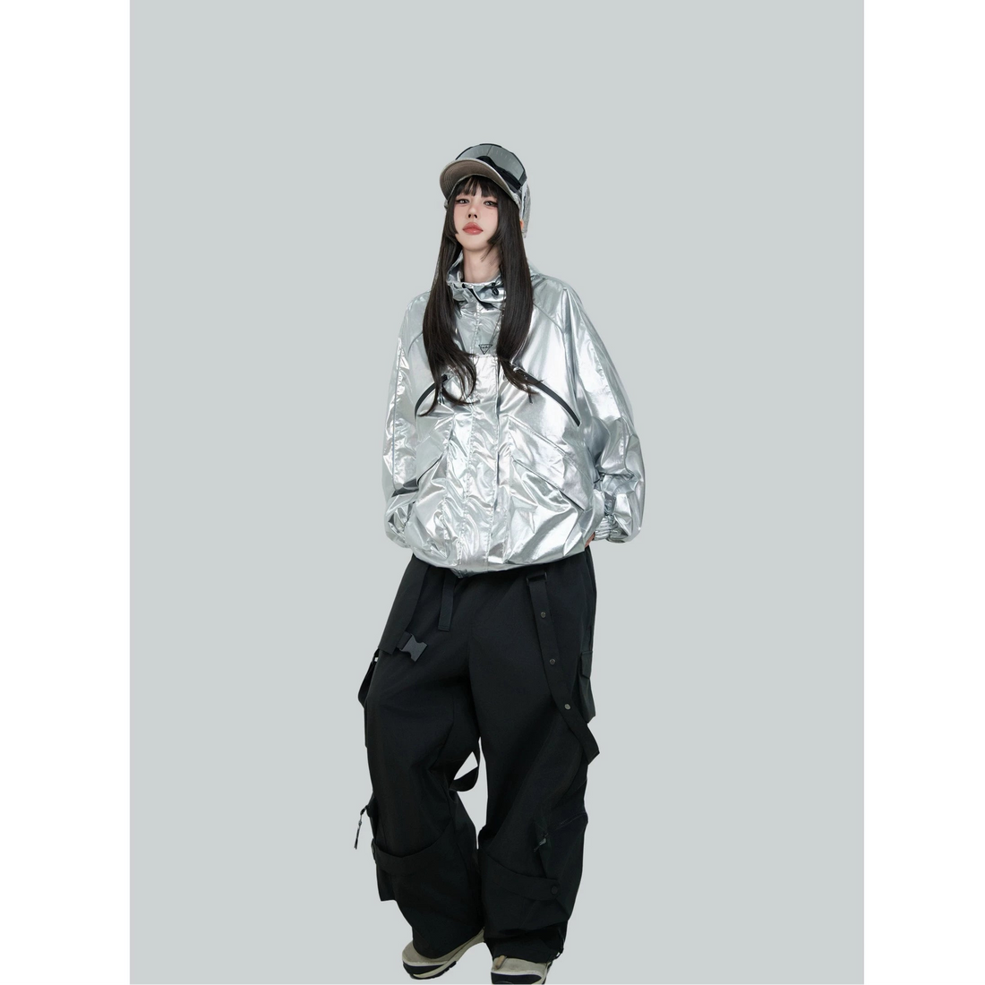 Person wearing a silver reflective jacket and black pants with &