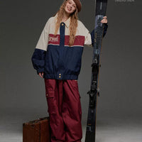 Person wearing a vintage-style ski outfit holding skis against a gray background