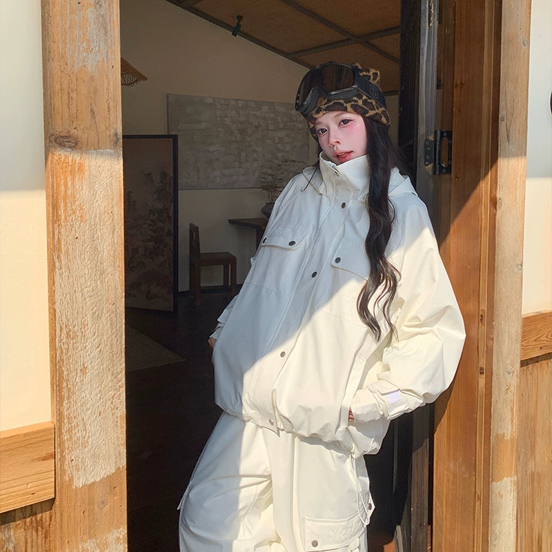 Person wearing a white skiing outfit and leopard print helmet standing in a wooden doorway.