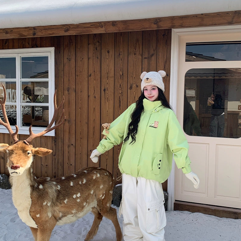 Person in a bright green jacket and white pants standing next to a deer in front of a wooden building.