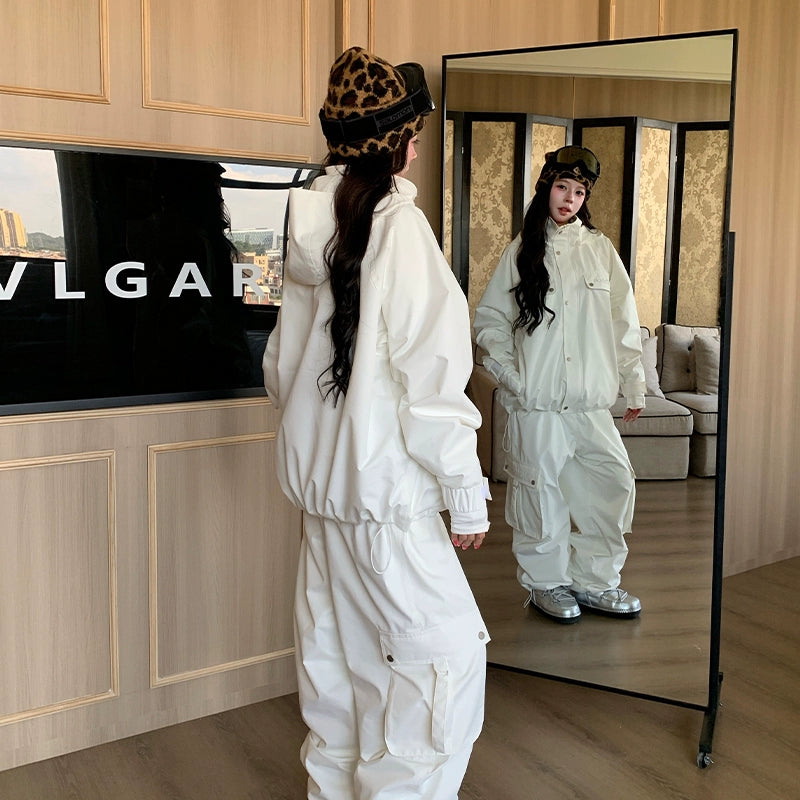 Person in a white skiing outfit standing in front of a mirror, wearing a leopard print hat.