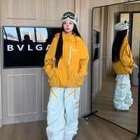 Person wearing a yellow jacket and white pants standing in front of a mirror.