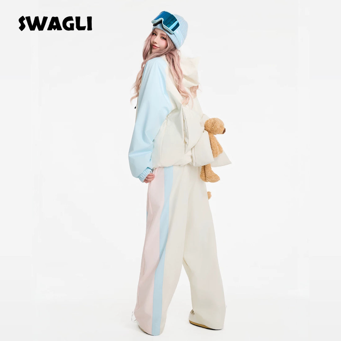 Person wearing a light blue and white onesie with a hood, holding a teddy bear, on a white background with &