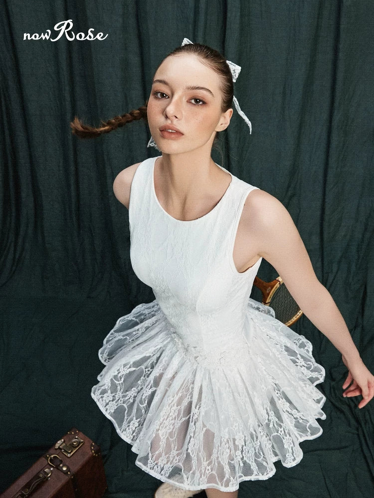 Woman in a white lace dress sitting against a dark curtain