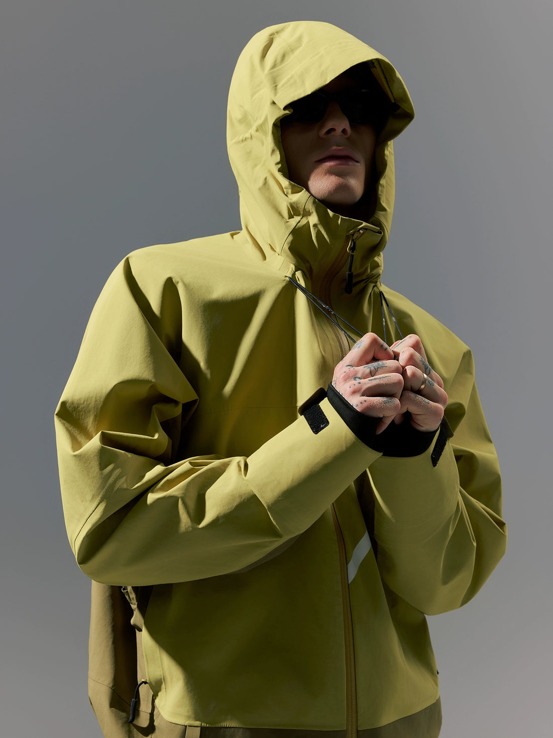 Person wearing a yellow raincoat against a gray background