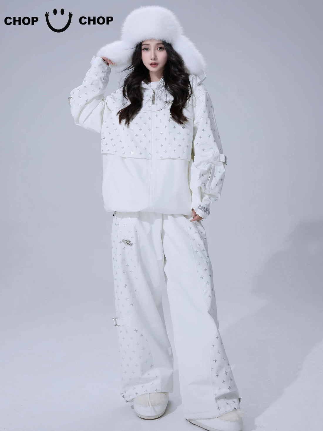A woman wearing a white skiing suit with a star pattern and a fur hood.