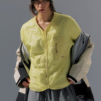 Person wearing a bright yellow jacket and holding bags against a gray background