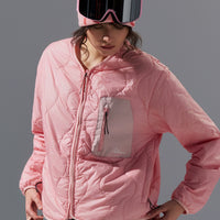 Person wearing a pink quilted jacket, gray pants, and a matching pink hat with goggles on a gray background