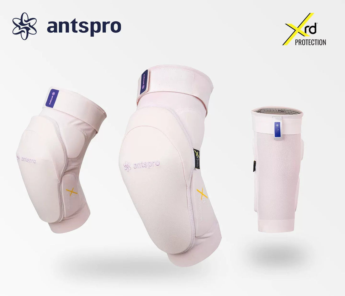 Three Antspro knee/leg protection sleeves in a very light pink color are displayed against a light gray background, with the Antspro logo, Xrd Protection badge, and Japanese text at the bottom.