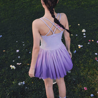Person wearing a purple dress standing in a grassy area with flowers