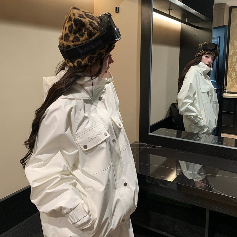 Person wearing a white skiing jacket and leopard print beanie looking at themselves in a mirror.