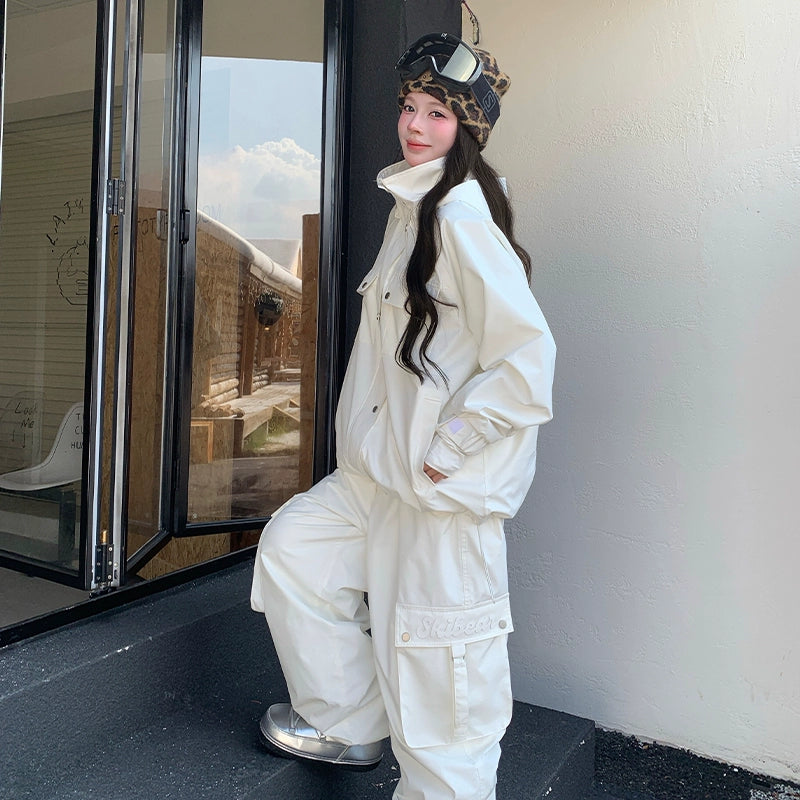 Person wearing a white skiing outfit with a helmet and goggles, standing indoors.