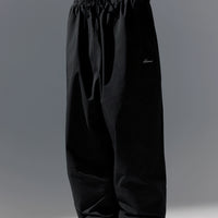 Black pants with a brand logo on a gray background