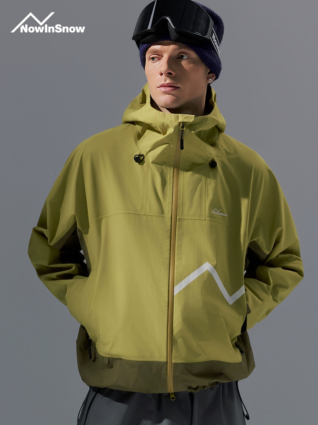 Person wearing a green jacket with a brand logo on a gray background